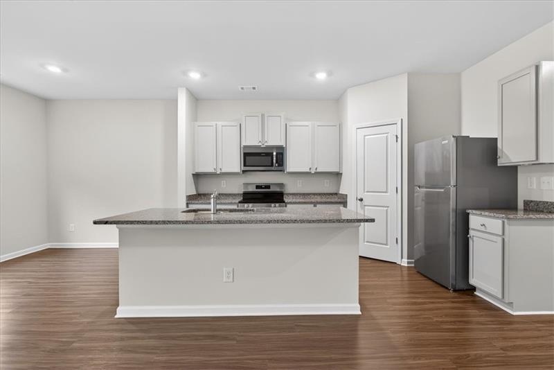 136 Brexley Drive Calhoun, GA 30701 - Photo 11 of 48 a kitchen with stainless steel appliances granite countertop a refrigerator a stove a sink and white cabinets with wooden floor