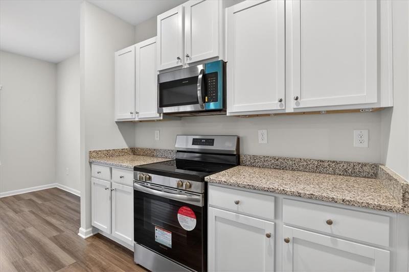 136 Brexley Drive Calhoun, GA 30701 - Photo 19 of 48 a kitchen with granite countertop white cabinets and a stove a microwave oven with wooden floor