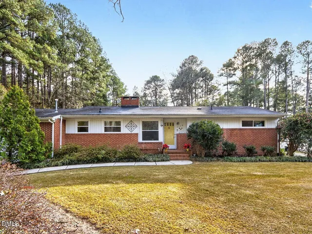 a front view of house with yard and trees in the background