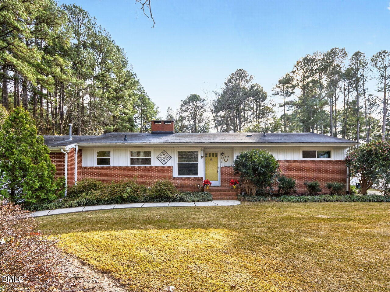 a front view of house with yard and trees in the background
