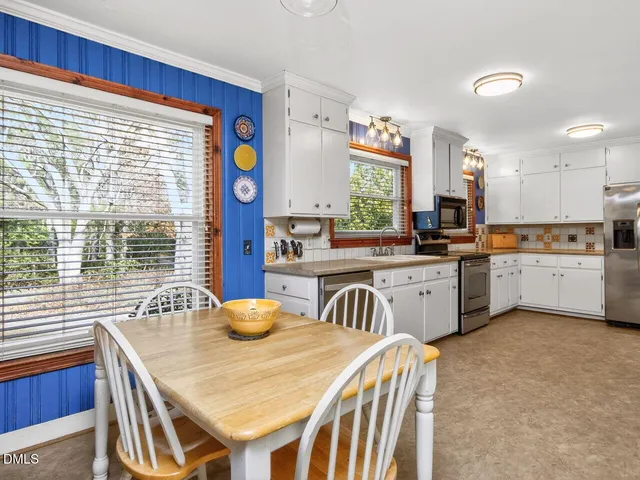 a kitchen with stainless steel appliances granite countertop a sink a stove a kitchen island with a dining table and chairs