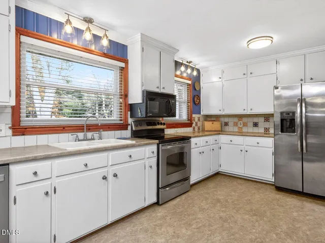 a kitchen with granite countertop white cabinets and white stainless steel appliances