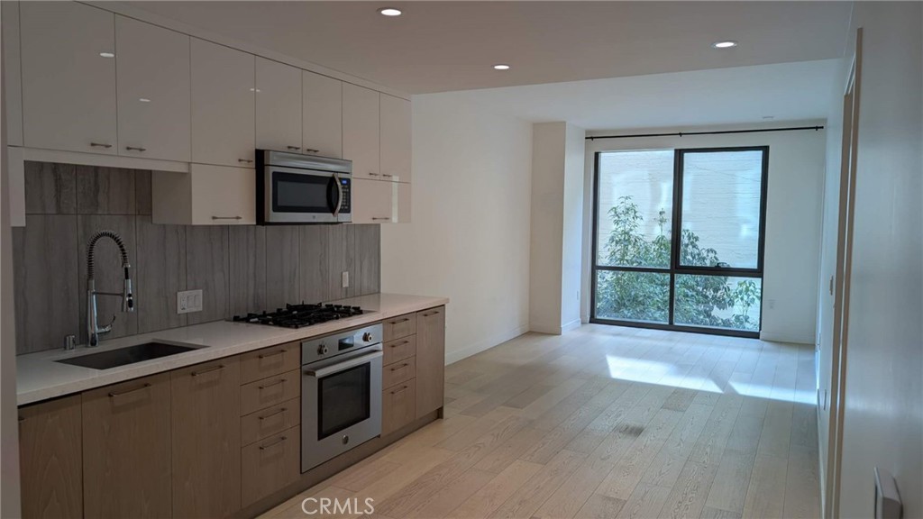 400 South Broadway, Unit 922 Los Angeles, CA 90013 - Photo 4 of 12 a kitchen with stainless steel appliances granite countertop a stove a sink and a microwave