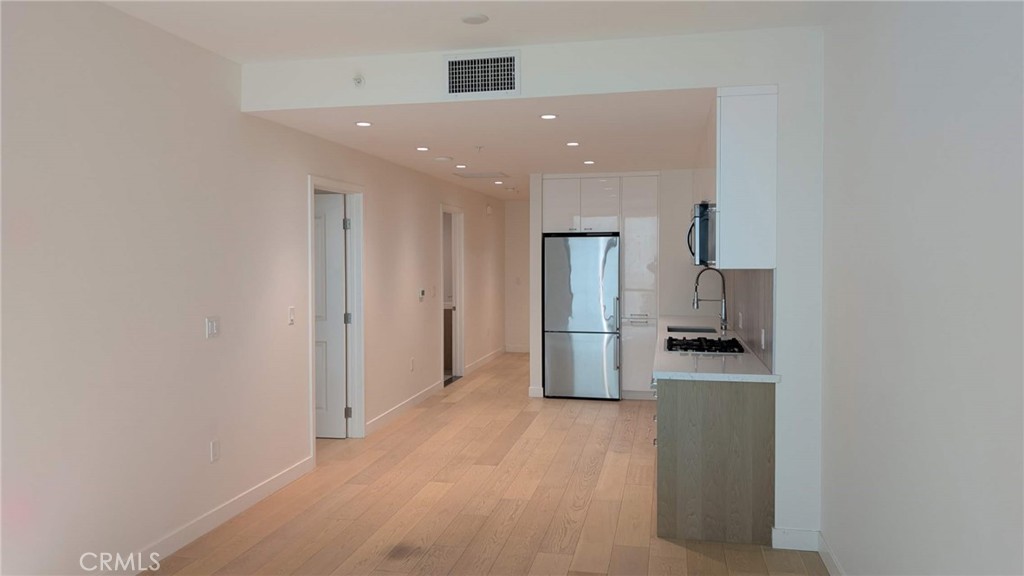 400 South Broadway, Unit 922 Los Angeles, CA 90013 - Photo 6 of 12 a kitchen with stainless steel appliances a refrigerator and wooden floor