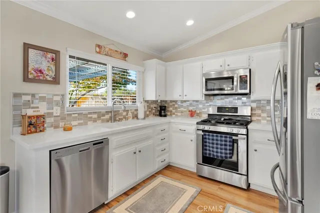 a kitchen with stainless steel appliances a stove a sink a refrigerator and a microwave