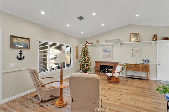 a living room with furniture a fireplace and potted plants with wooden floor