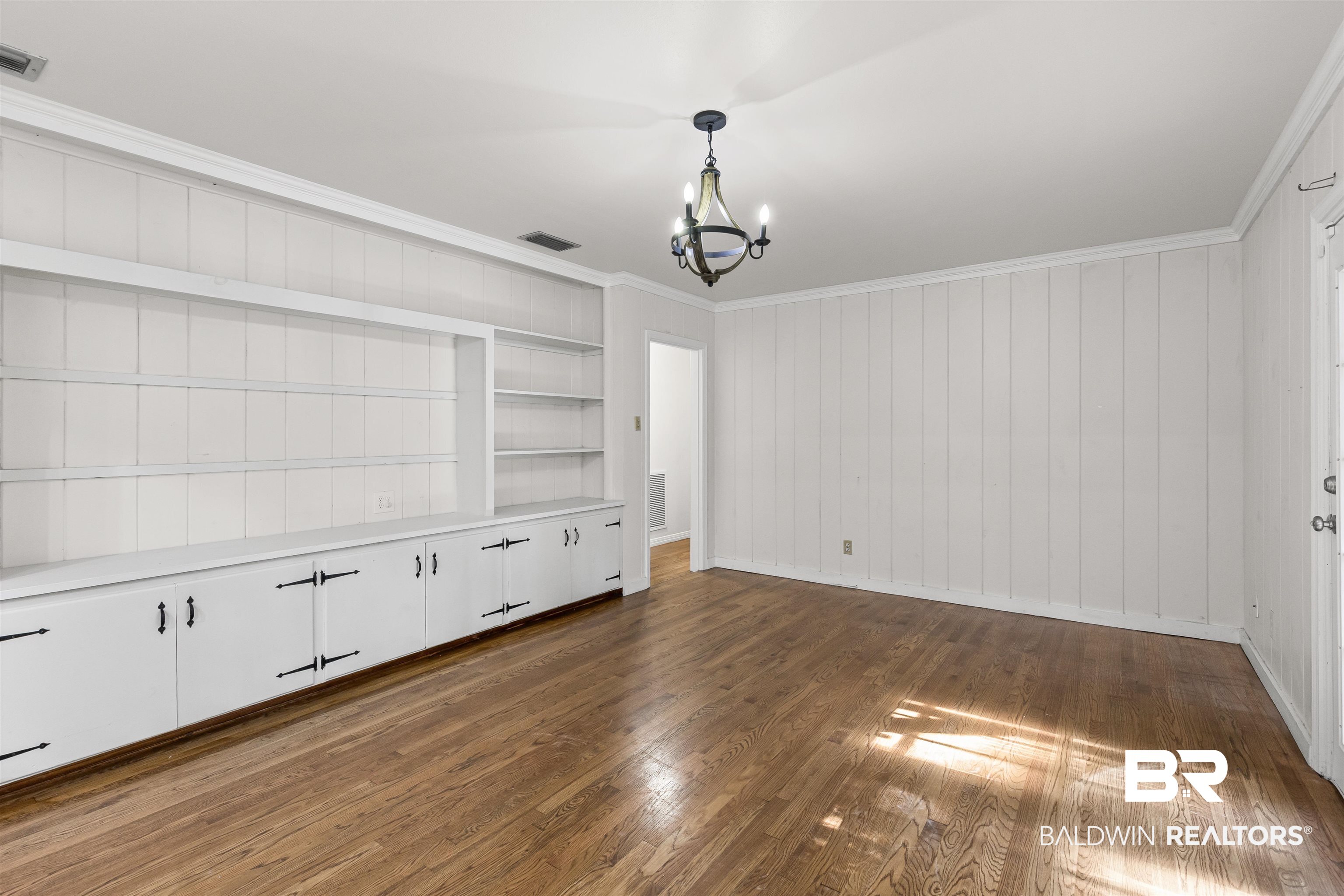 1108 Locarno Street Mobile, AL 36608 - Photo 10 of 24 Unfurnished dining area with wood finished floors, a chandelier, ornamental molding, wooden walls, and built in features