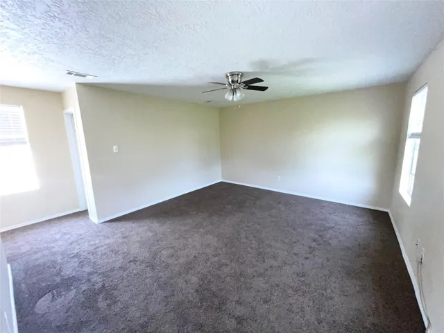 an empty room with a window and a fan