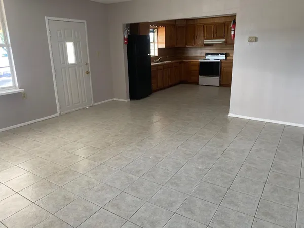 an empty room with kitchen view and windows