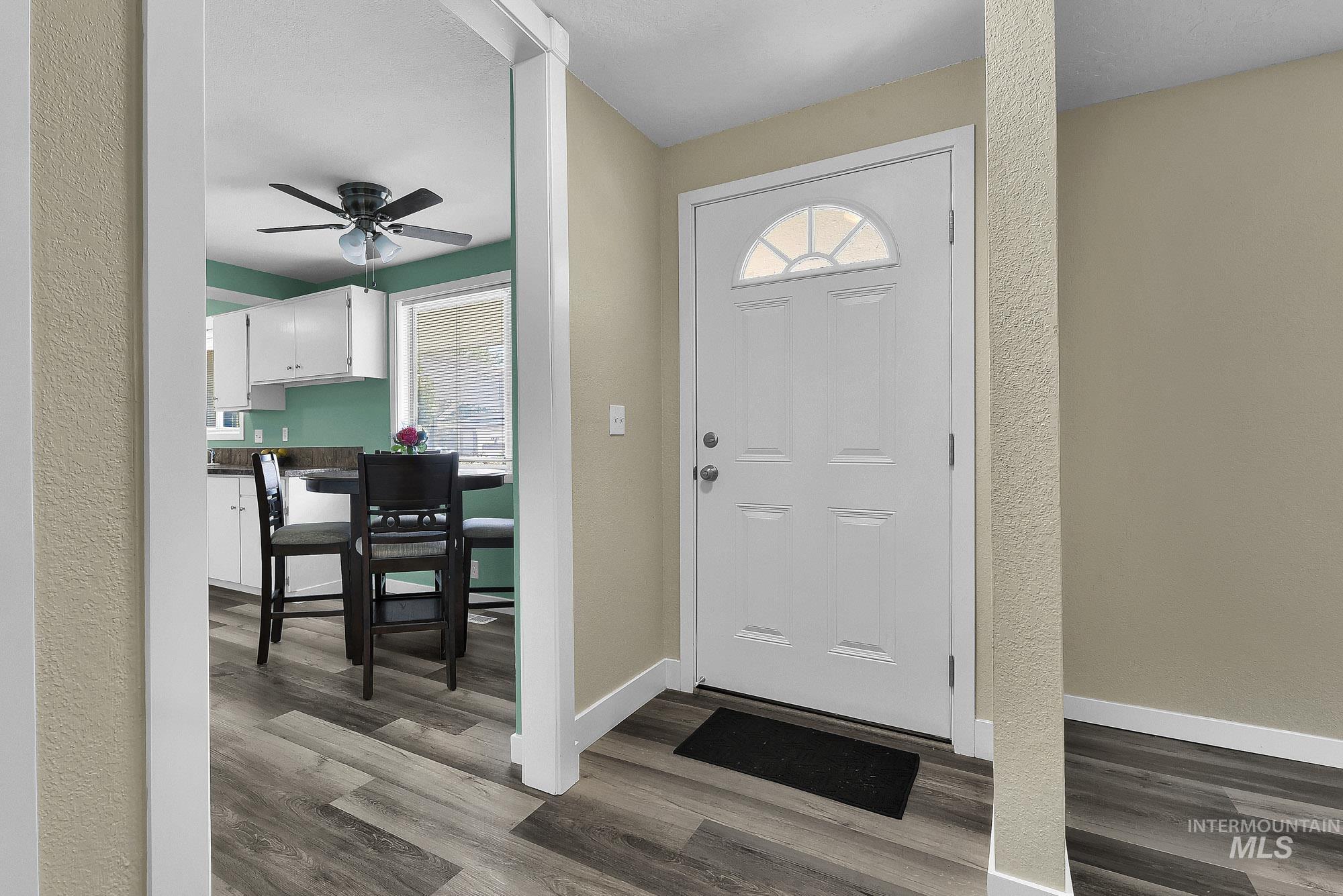 5755 Chuckwagon Road Nampa, ID 83686 - Photo 12 of 50 Wood-finish flooring throughout, white paneled entry door with an arched transom, and a kitchen with white cabinetry and a ceiling fan