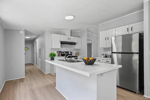 a kitchen with refrigerator a sink a stove and cabinets