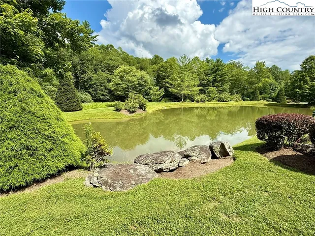 a front view of a house with a garden and lake view