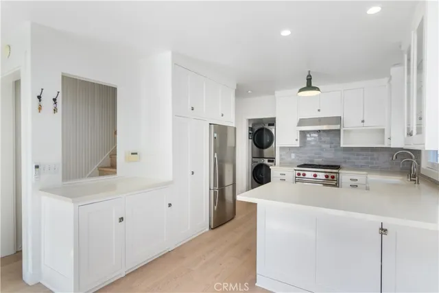 a kitchen with refrigerator a stove a sink and white cabinets