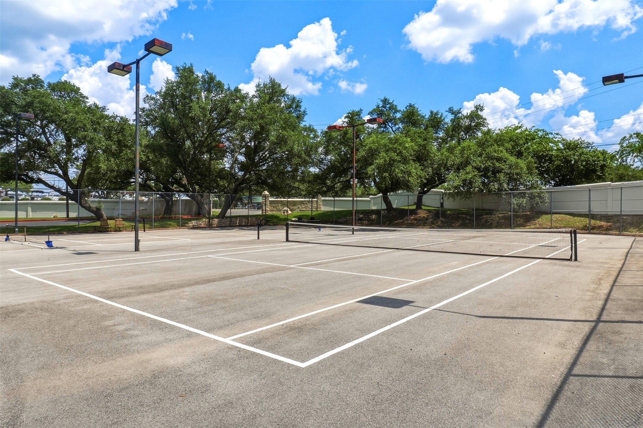 2918 Ranch Road 620, Unit 265 Austin, TX 78734 - Photo 36 of 40 An outdoor tennis court awaits, complete with lighting for evening play, framed by verdant trees.