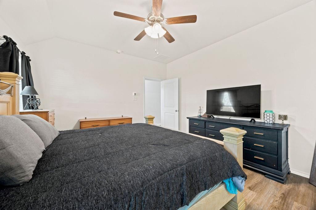 822 Ramble Road Lavon, TX 75166 - Photo 25 of 35 Vaulted ceiling bedroom with wood-finish flooring, a ceiling fan with light fixture, and neutral wall tones