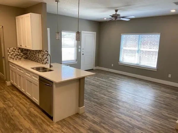 a kitchen with stainless steel appliances granite countertop a sink a stove a refrigerator and island with wooden floor