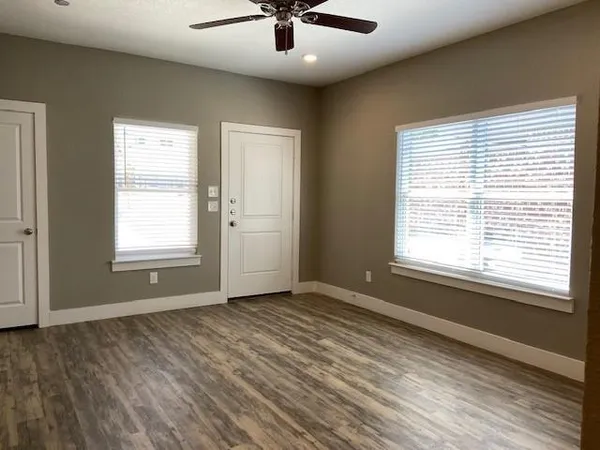 a view of an empty room with a window and wooden floor