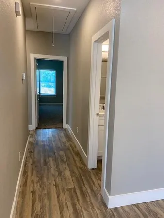 a view of a hallway with wooden floor and a bathroom