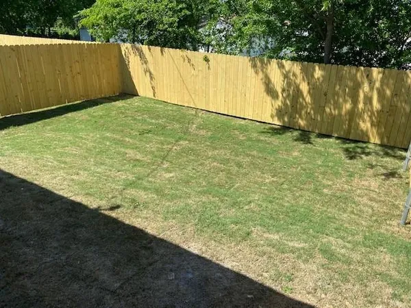a view of yard with swimming pool and wooden fence
