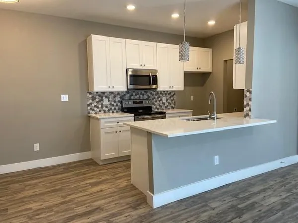 a kitchen with stainless steel appliances a sink a stove a microwave and cabinets