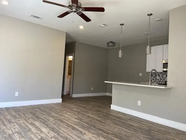 a view of a room with a ceiling fan and hardwood floor