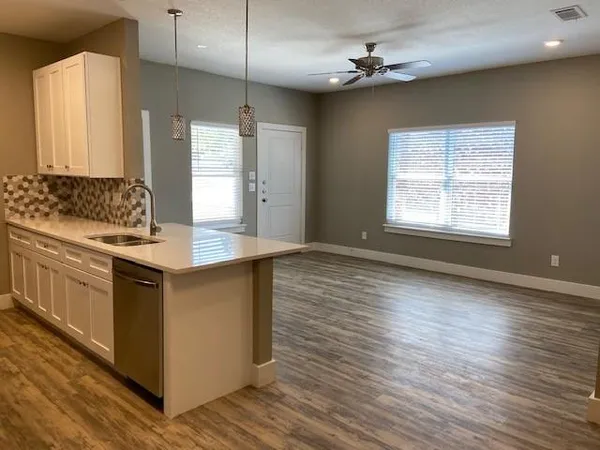 a kitchen with stainless steel appliances granite countertop a sink cabinets and wooden floor