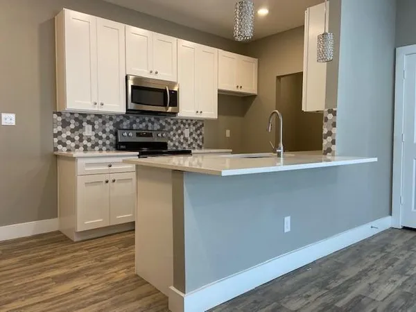 a kitchen with granite countertop white cabinets and black stainless steel appliances
