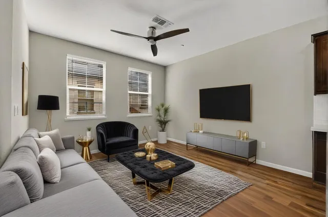 a living room with furniture a flat screen tv and a window