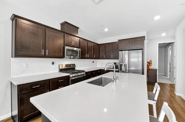 a kitchen with stainless steel appliances granite countertop a sink a stove top oven a counter space and cabinets