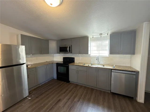 a kitchen with a sink a refrigerator a microwave and cabinets