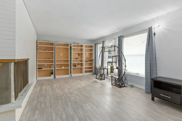 an empty room with wooden floor closet and windows