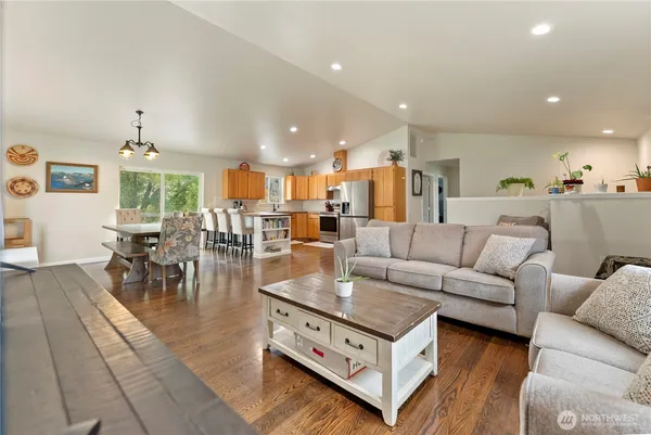 a living room with furniture a wooden floor and kitchen view