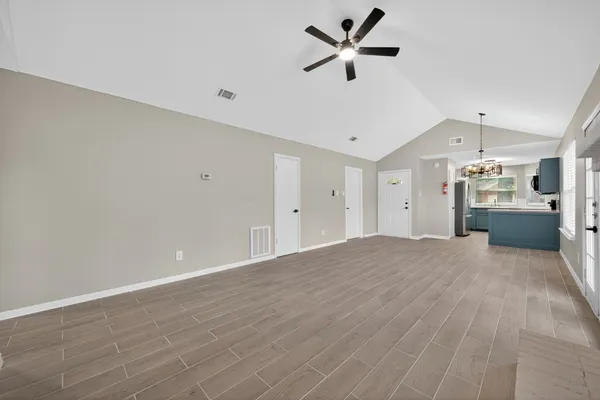 a view of a livingroom with a ceiling fan & kitchen view