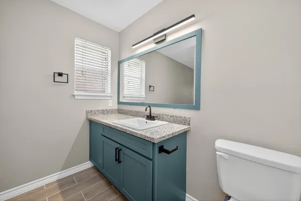 a bathroom with a granite countertop sink and a toilet