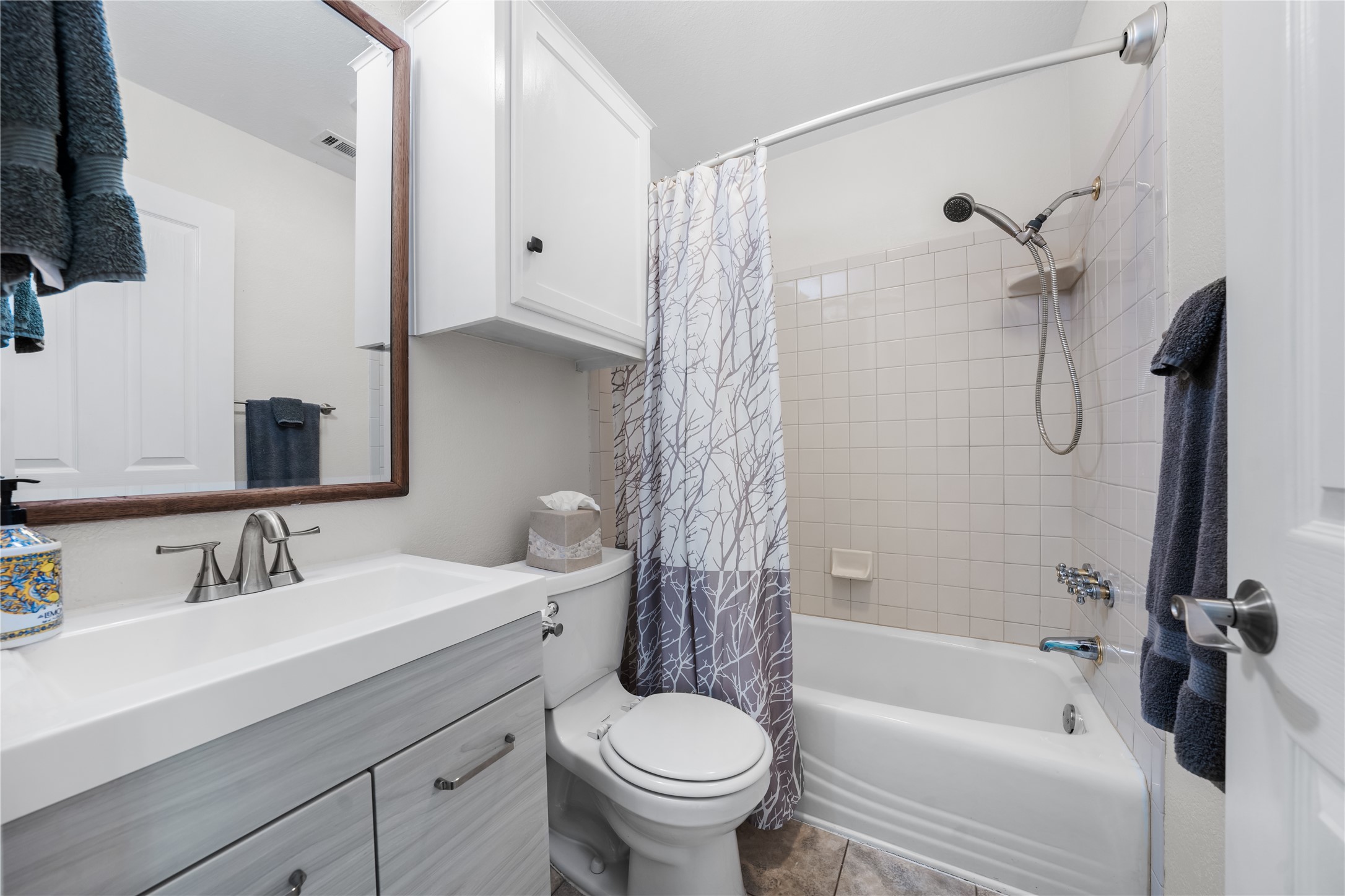 7670 Nez Perce Trace Manor, TX 78653 - Photo 16 of 40 Bathroom featuring toilet, shower / bathtub combination with curtain, vanity, and visible vents