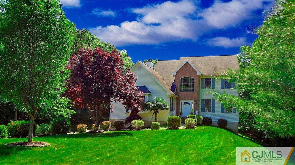 a front view of a house with a garden and trees