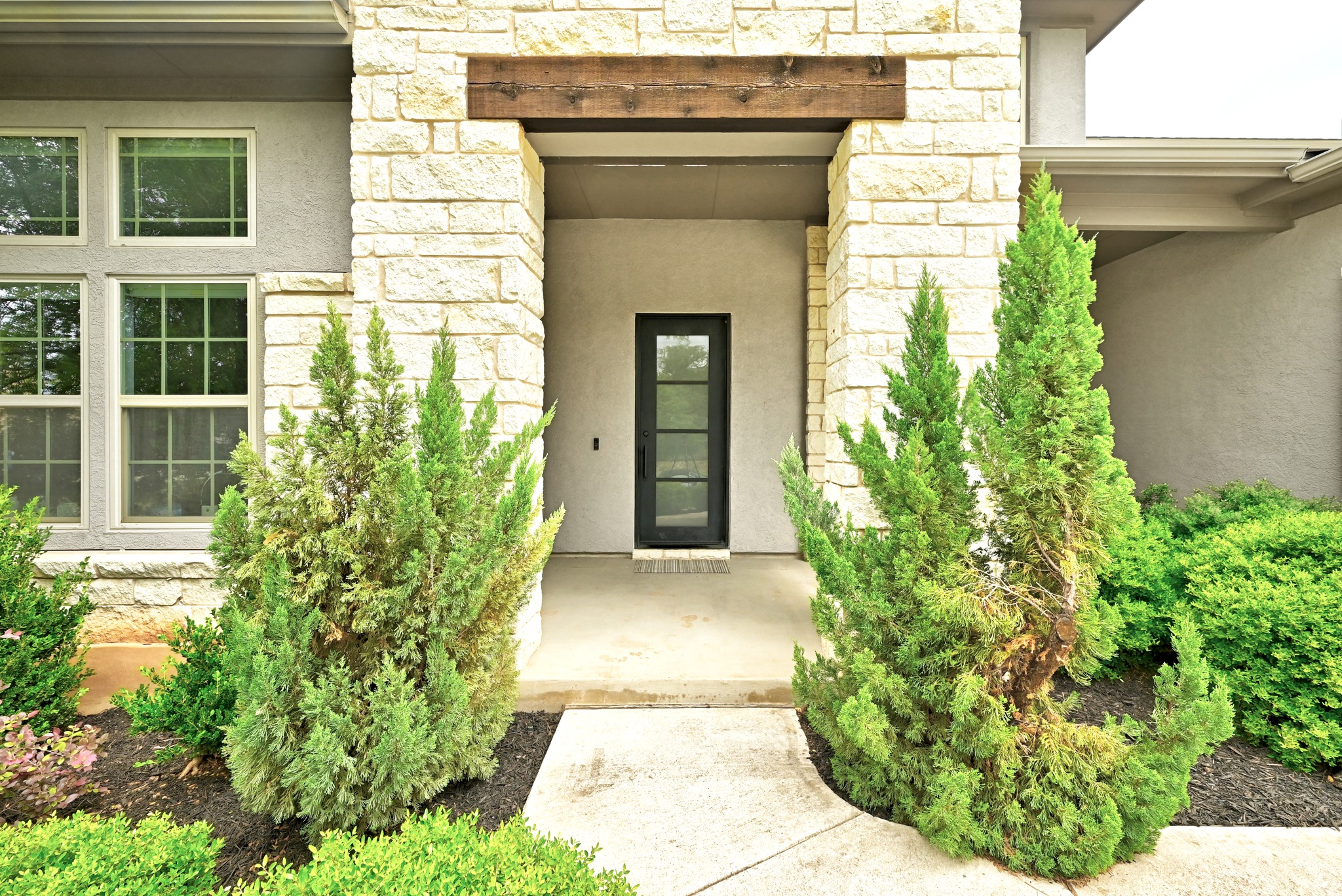9008 Harper Rae Drive Austin, TX 78717 - Photo 4 of 39 Stone and stucco exterior featuring a recessed entry with a dark-framed glass paneled door