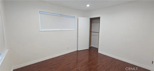 a view of an empty room with wooden floor and closet