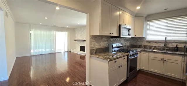 a kitchen with stainless steel appliances granite countertop a stove a sink and white cabinets
