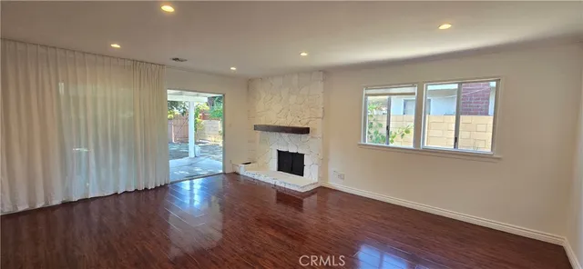 a view of a livingroom with wooden floor fireplace and window