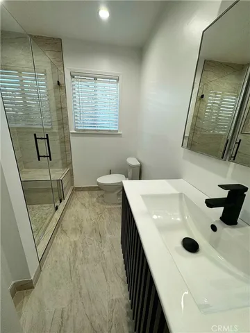 a bathroom with a sink a toilet a mirror and shower