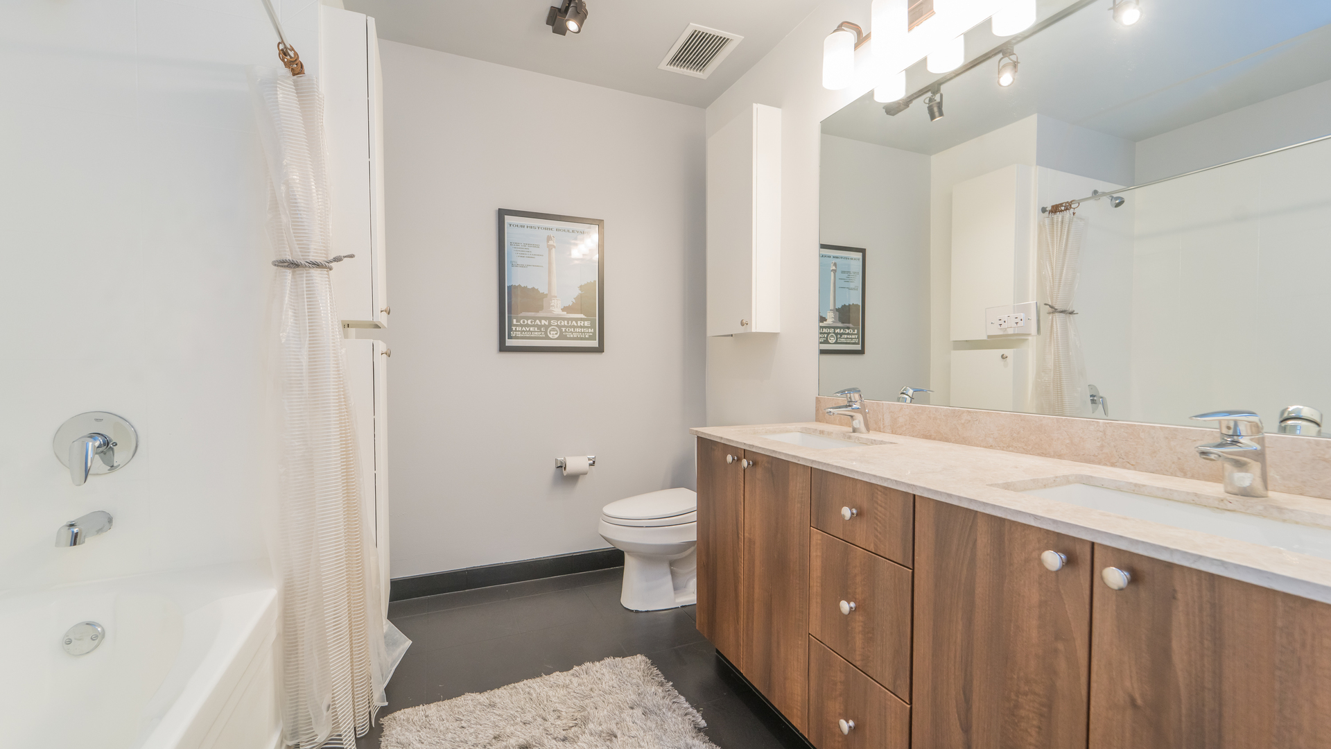 235 West Van Buren Street, Unit 1519 Chicago, IL 60607 - Photo 8 of 10 a spacious bathroom with a double vanity sink toilet mirror and bathtub