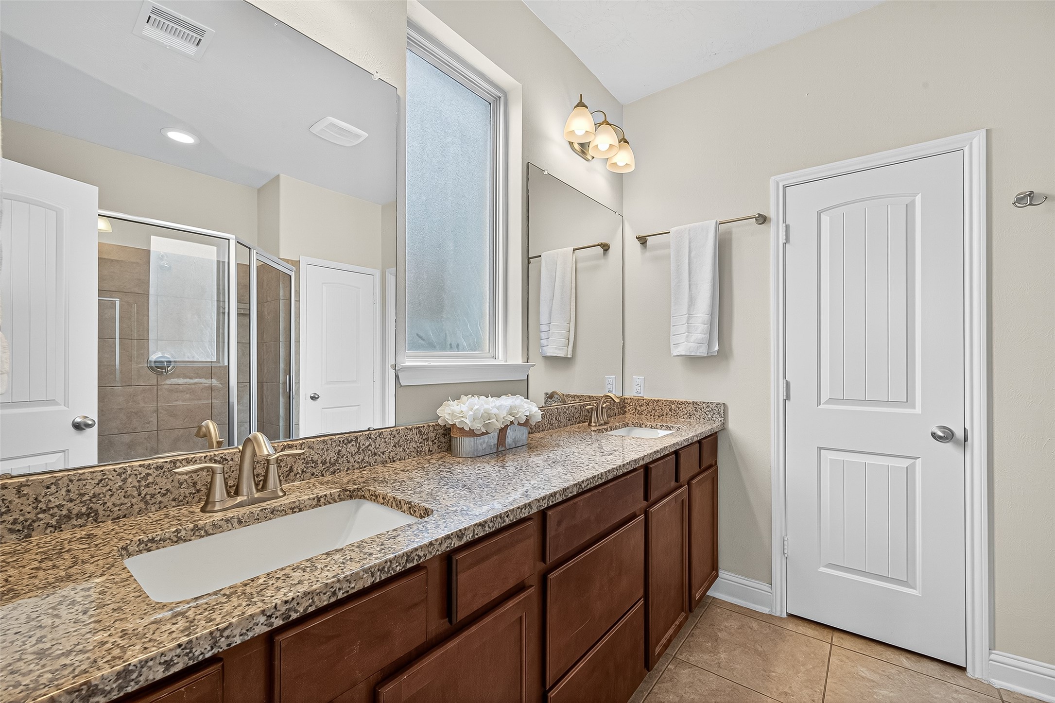 8107 Lockridge Terrace Lane Cypress, TX 77433 - Photo 32 of 50 Another angle of the serene primary bath showcases the rich cabinetry, granite countertops, and framed mirror that elevate the space with elegance. The oversized window allows soft natural light to pour in while maintaining privacy—perfect for a peaceful start or end to your day.