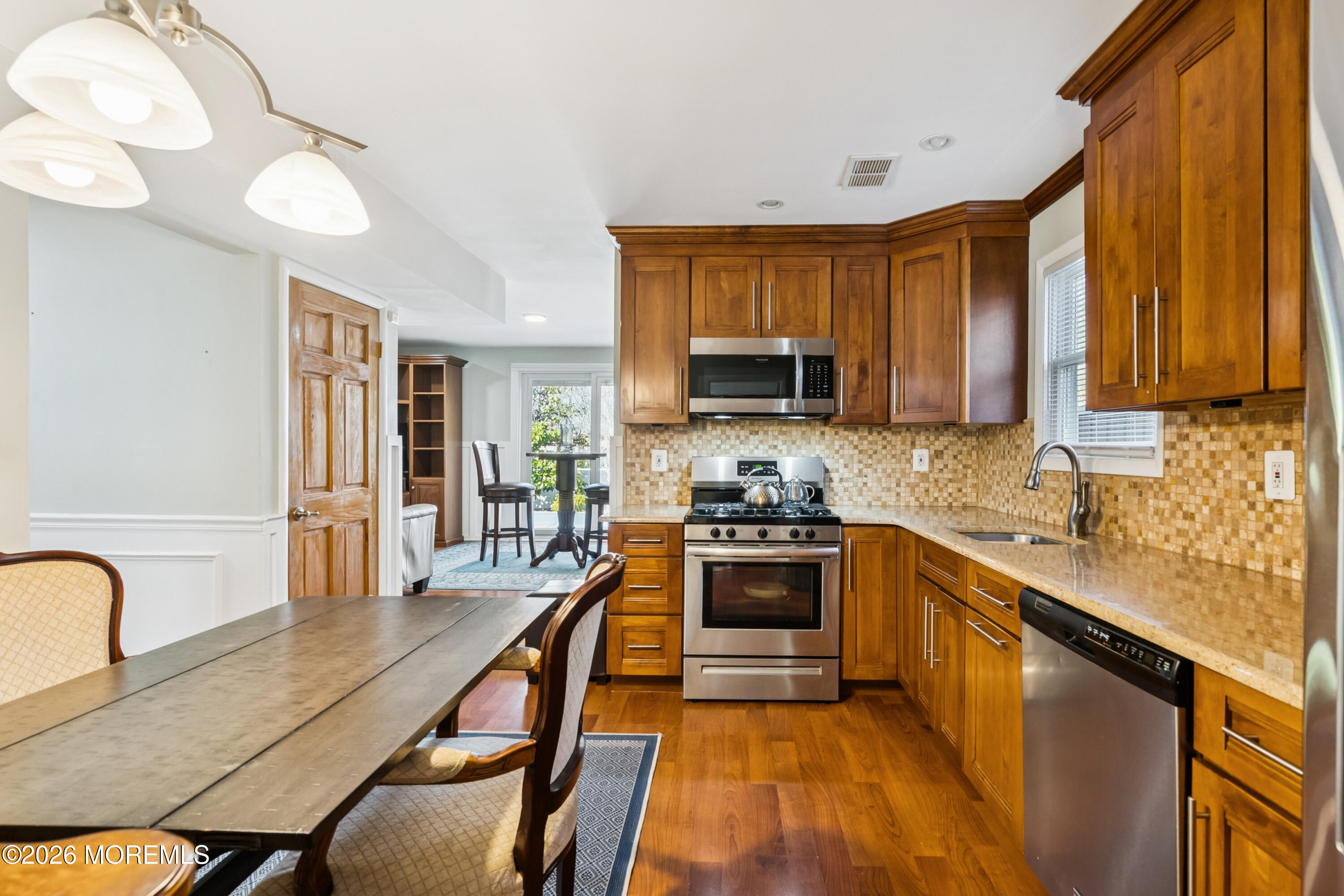 5 Liberty Court Howell, NJ 07731 - Photo 10 of 30 a kitchen with stainless steel appliances granite countertop a stove top oven a sink dishwasher a dining table and chairs with wooden floor