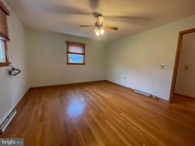 an empty room with wooden floor and windows