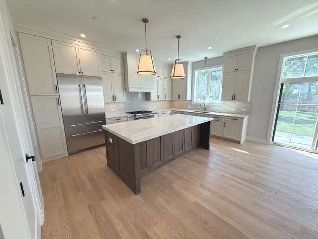 a kitchen with stainless steel appliances granite countertop a stove a sink a refrigerator and wooden floor