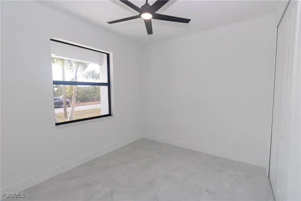 an empty room with windows and fan