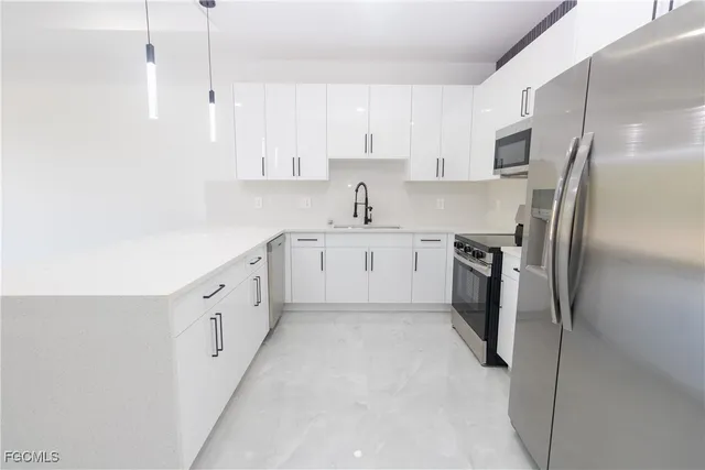 a kitchen with stainless steel appliances a refrigerator sink and white cabinets