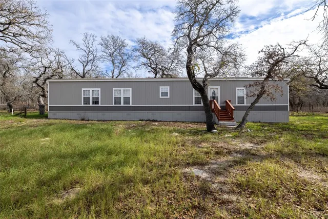 a view of a house with backyard and wooden fence