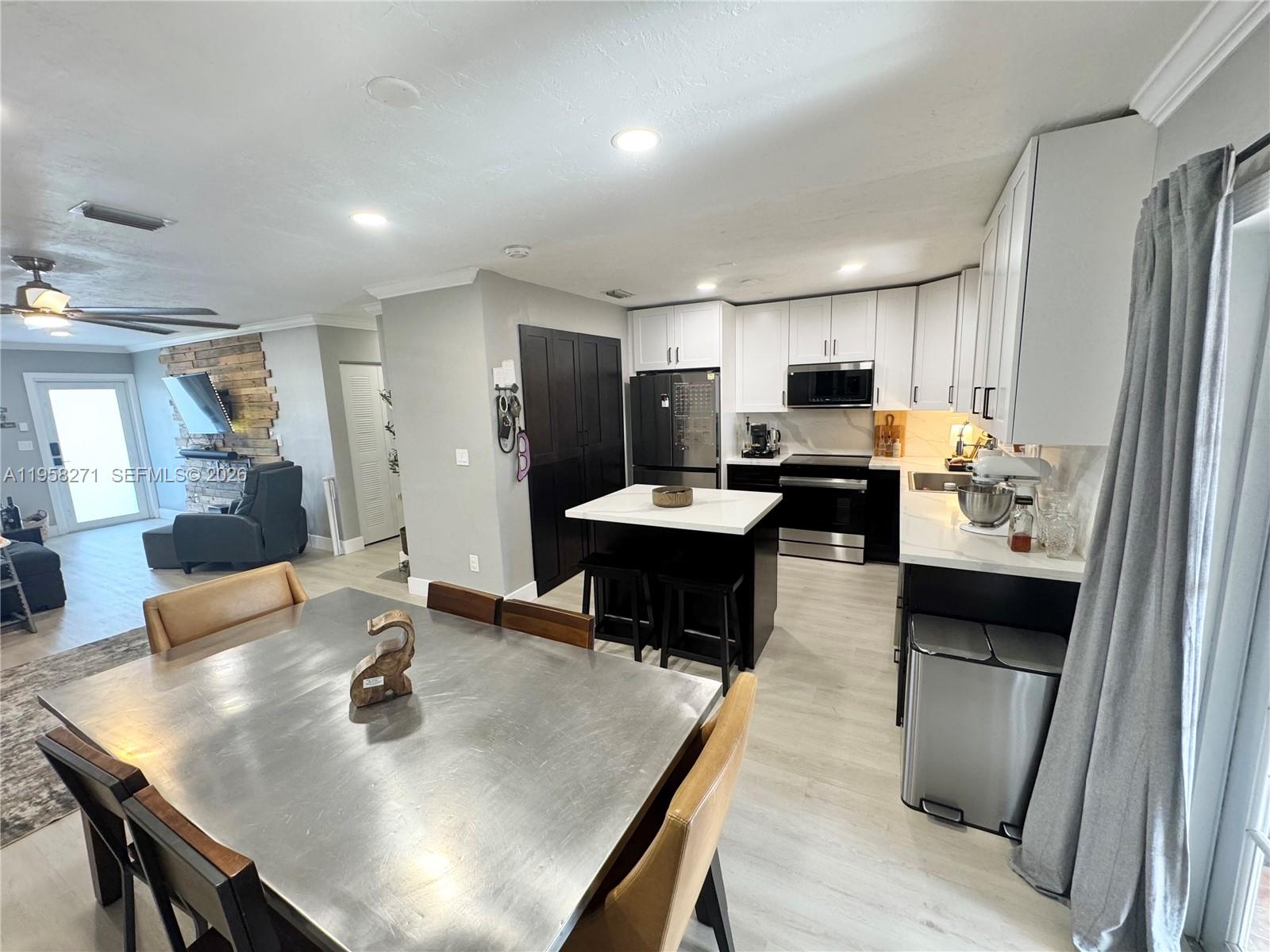 14849 Southwest 114th Court Miami, FL 33176 - Photo 4 of 23 a kitchen with kitchen island a stove a refrigerator a sink a dining table and chairs